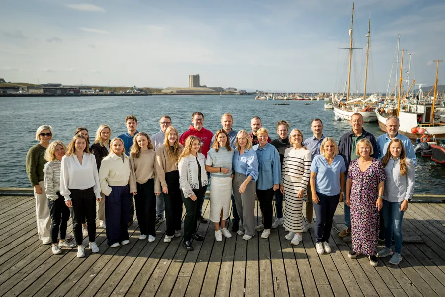 En gruppe mennesker står på en kai i solskinn